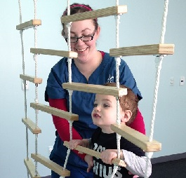 Therapist working with boy climbing rope ladder