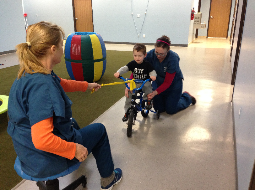 Boy learning to ride bike with therapists