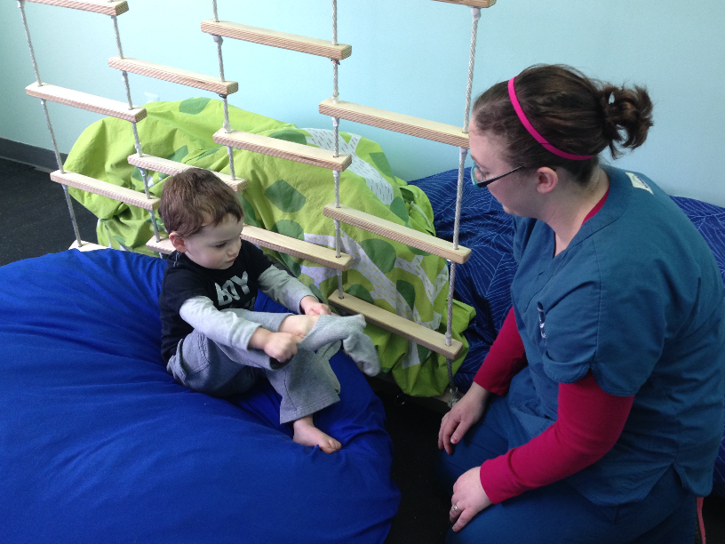 Therapist with boy putting on socks