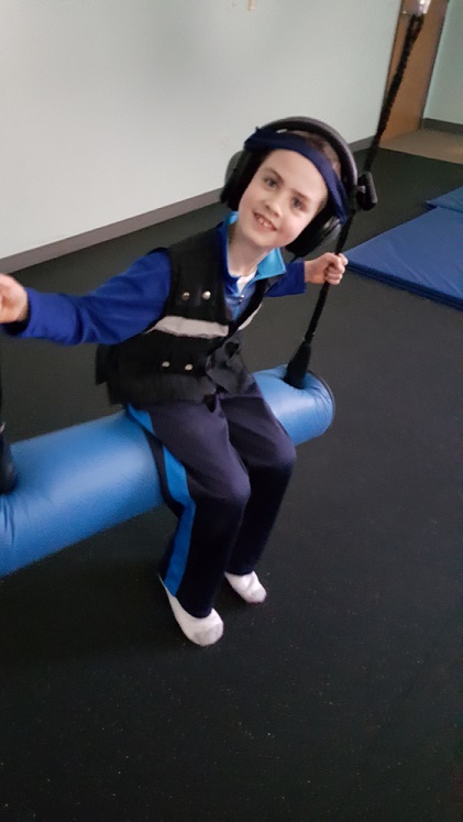 SA sitting on swing with Therapeutic Listening headphones