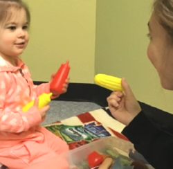 A young girl and woman playing with toy foods and condiments