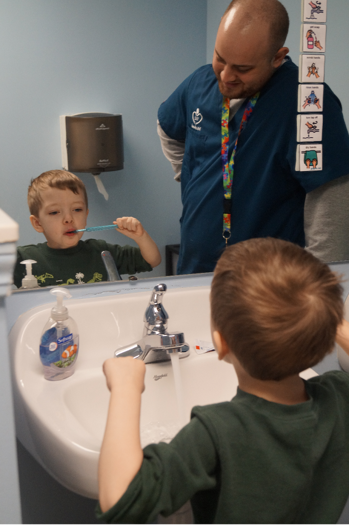 Boy learning to brush teeth with therapist