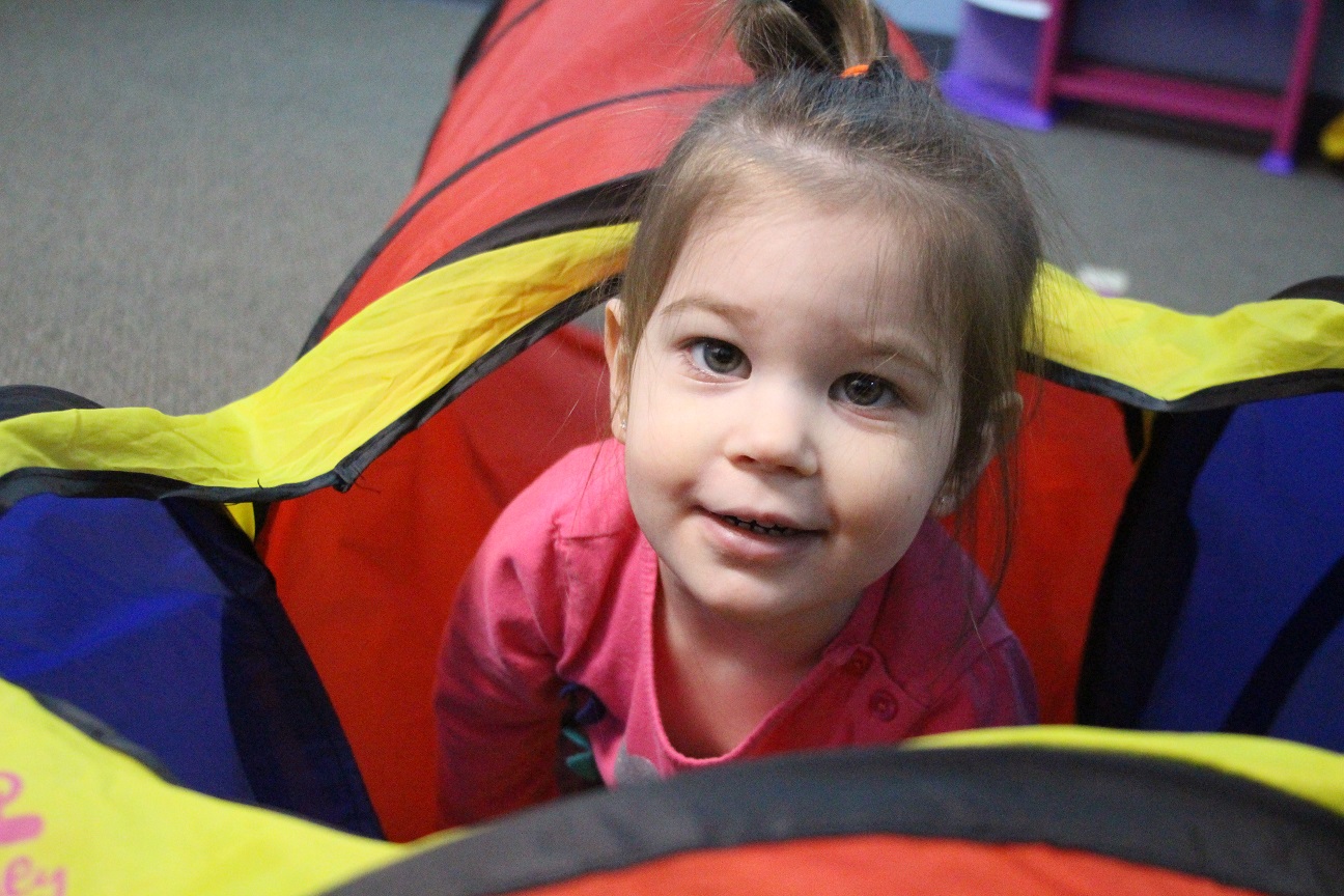 Girl peeking out of crawling tube