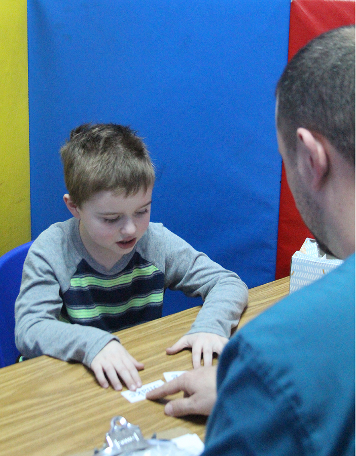 Therapist and boy working in cubicle