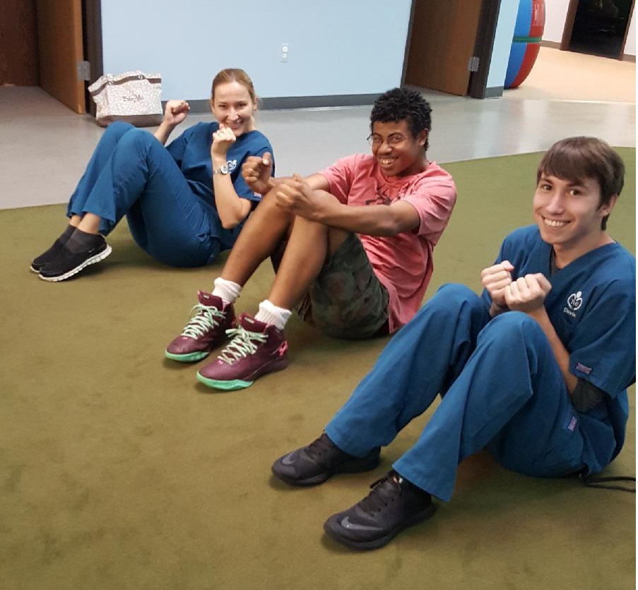 Therapists and teenage boy performing strength training exercises
