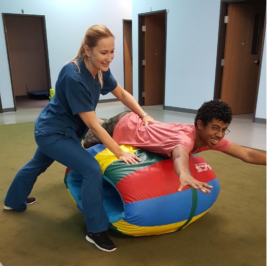 Therapist and teenage boy on exercise barrel