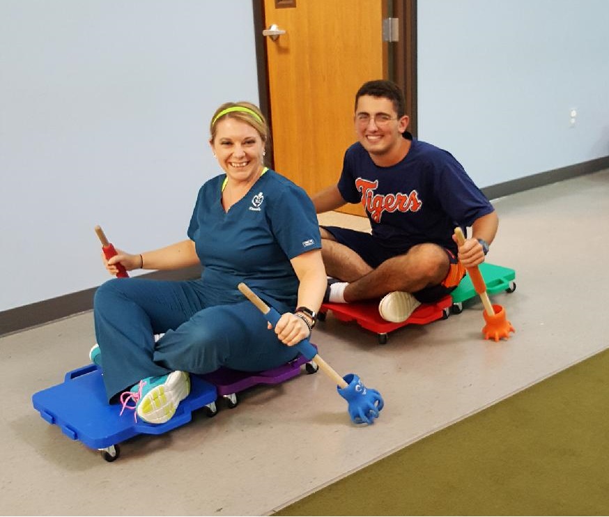 Therapist and teenage boy on scooter boards