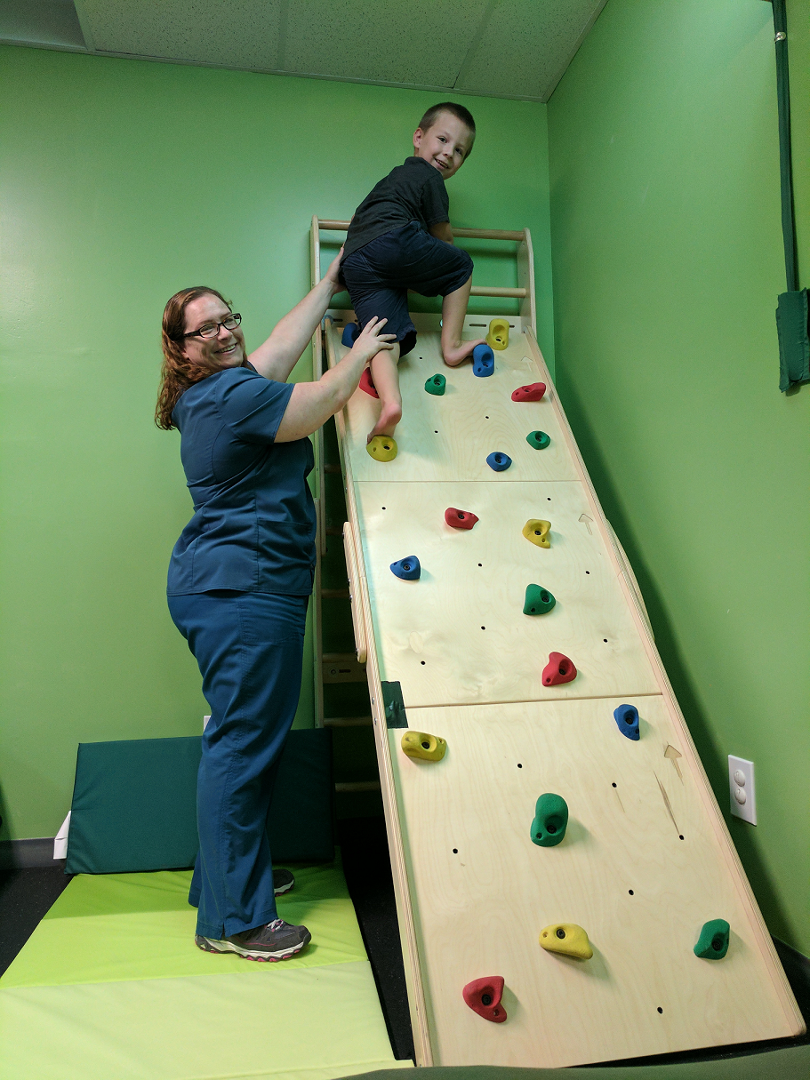 Therapist assisting boy on rock climbing wall