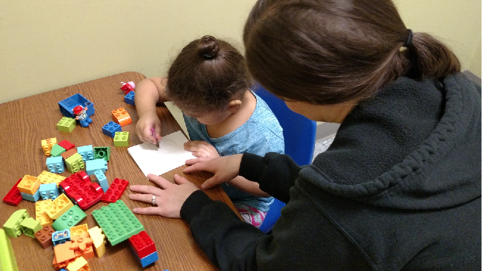 Therpist working with girl and blocks
