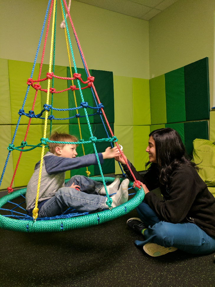 Therapist working with boy on web swing